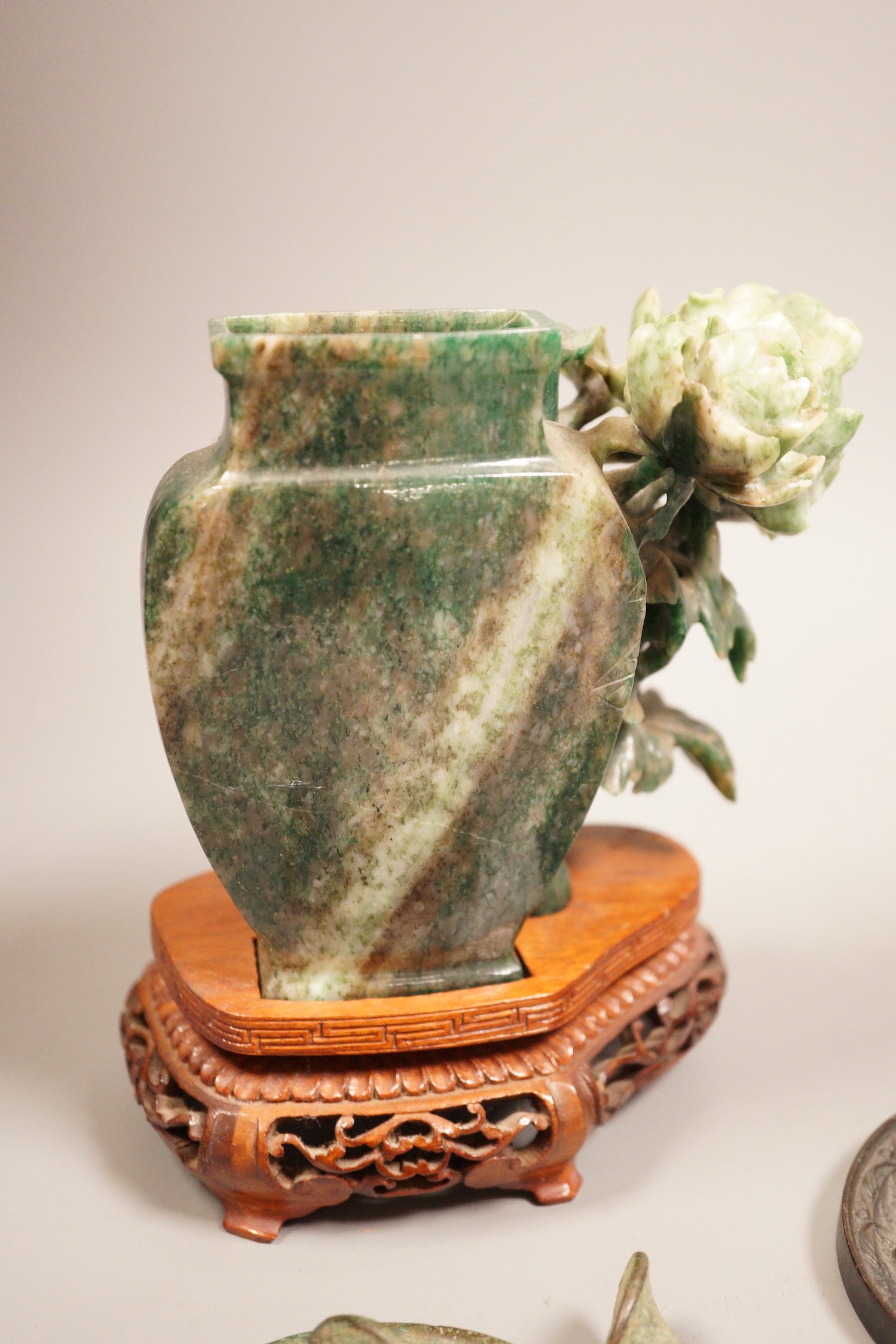 A Chinese bronze mirror, 11cm diameter, a jadeite floral carving on stand with a metal relief plaque, and a pair of bracelets